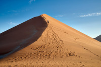 group of people climbing up sand dune of Namib desert