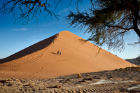 group of people climbing up sand dune of Namib desert
