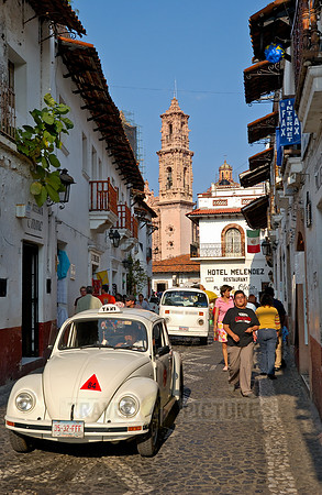 City view with San Sebastian y Santa Prisca Church in the background and VW Beetles as taxis