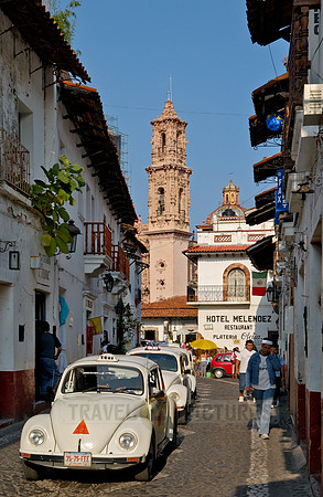City view with San Sebastian y Santa Prisca Church in the background and VW Beetles as taxis