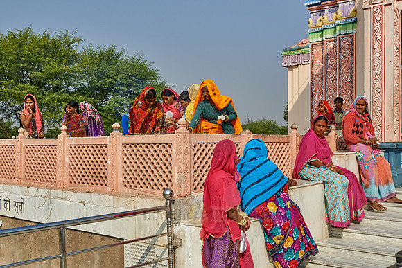 Women in colorful saris in front typical colorful temple