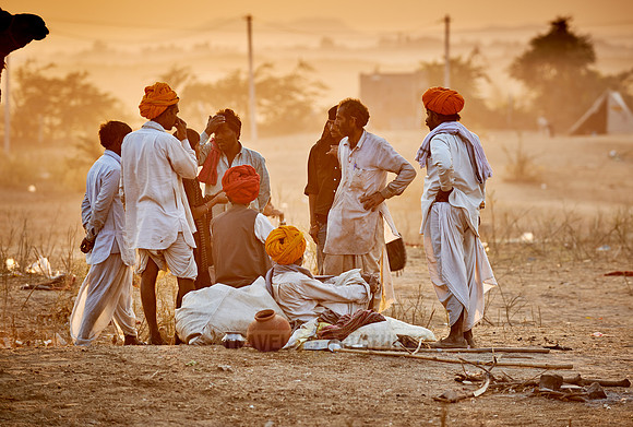 nomadic tribe men with traditional turbans haggle for prices