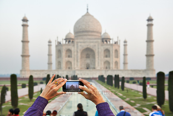 hands with mobile phone making photo of Taj Mahal