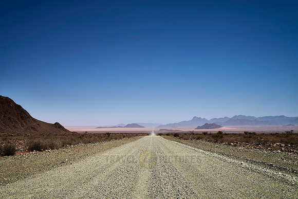 straight deserted gravel road in desert landscape