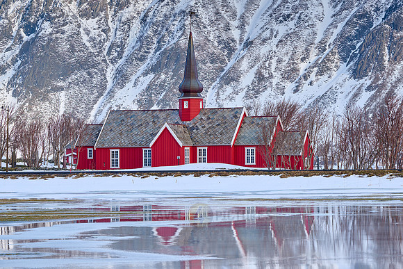 Red church of Flakstad with reflection in the water