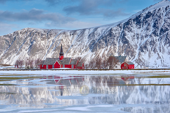Red church of Flakstad with reflection in the water