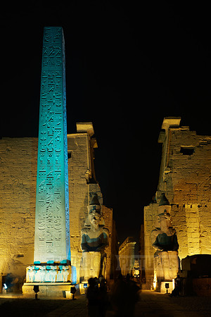 night shot of illuminated statues and obelisk of Ramesses II. in front of first Pylon