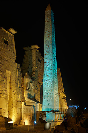 night shot of illuminated statues and obelisk of Ramesses II. in front of first Pylon