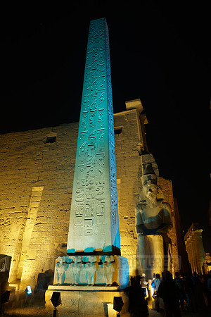 night shot of illuminated statues and obelisk of Ramesses II. in front of first Pylon