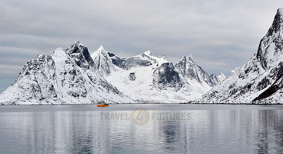 yellow vessel in front of spectacular winter landscape in the bay of Hamnoy