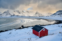 red hut in winter landscape with sea and mountains at Sandbotnen, Lofoten,