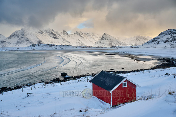red hut in winter landscape with sea and mountains at Sandbotnen, Lofoten,