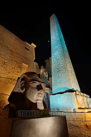 night shot of illuminated statues and obelisk of Ramesses II. in front of first Pylon