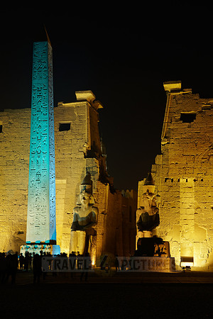 night shot of illuminated statues and obelisk of Ramesses II. in front of first Pylon