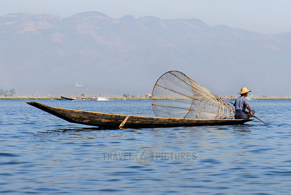 one leg rowing boat with fisherman with his conical trap