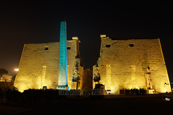 night shot of illuminated statues and obelisk of Ramesses II. in front of first Pylon